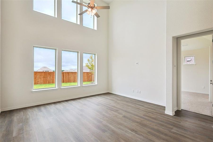 Empty room featuring ceiling fan, dark hardwood / wood-style floors, and a towering ceiling