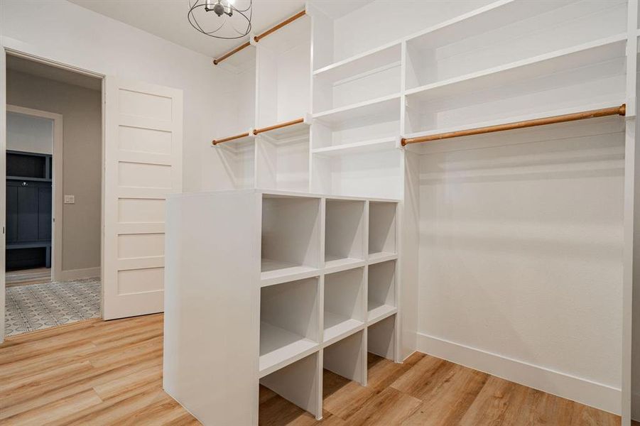 Example of builders Spacious closet featuring hardwood / wood-style floors and an inviting chandelier