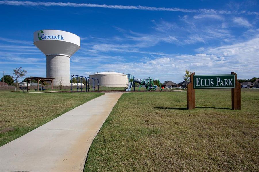 Ellis Park features a concrete pathway, playground equipment, a wooden pergola, and a visible water tower