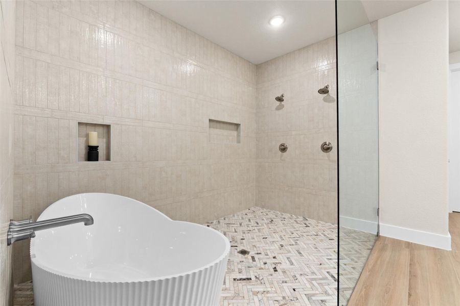 Bathroom with wood finished floors, a soaking tub, walk in shower, tile walls, and recessed lighting