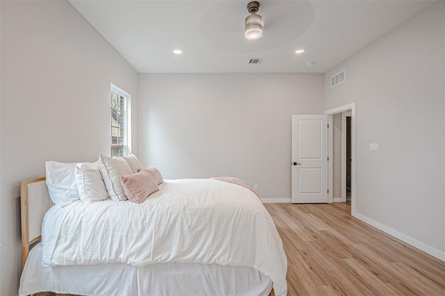 Bedroom with light wood-style flooring, ceiling fan, and recessed lighting