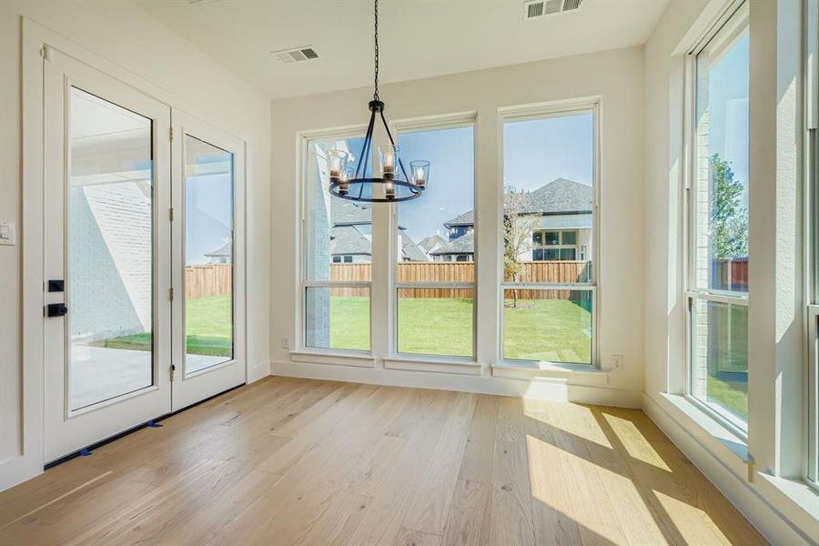 Unfurnished dining area with light wood finished floors, healthy amount of natural light, and a chandelier Unfurnished dining area with light wood finished floors, healthy amount of natural light, and a chandelier