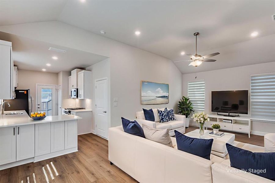 Living area with lofted ceiling, light wood-style floors, a ceiling fan, and recessed lighting Living area with lofted ceiling, light wood-style floors, a ceiling fan, and recessed lighting