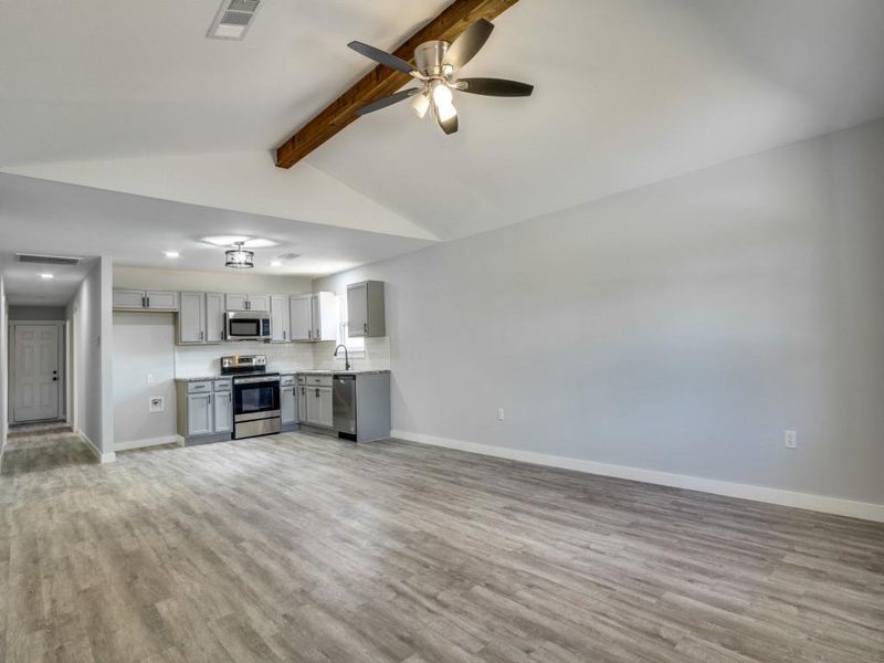 Unfurnished living room featuring ceiling fan, sink, light hardwood / wood-style flooring, and lofted ceiling with beams Unfurnished living room featuring ceiling fan, sink, light hardwood / wood-style flooring, and lofted ceiling with beams