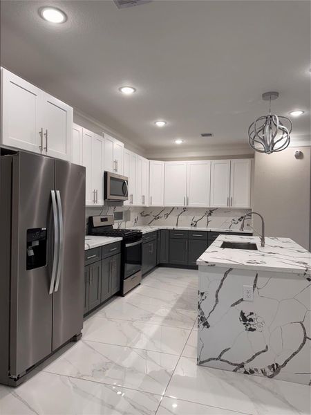 Modern kitchen featuring sleek stainless steel appliances, elegant two-tone cabinetry, and stunning marble-patterned countertops with matching backsplash and flooring. Modern kitchen featuring sleek stainless steel appliances, elegant two-tone cabinetry, and stunning marble-patterned countertops with matching backsplash and flooring.
