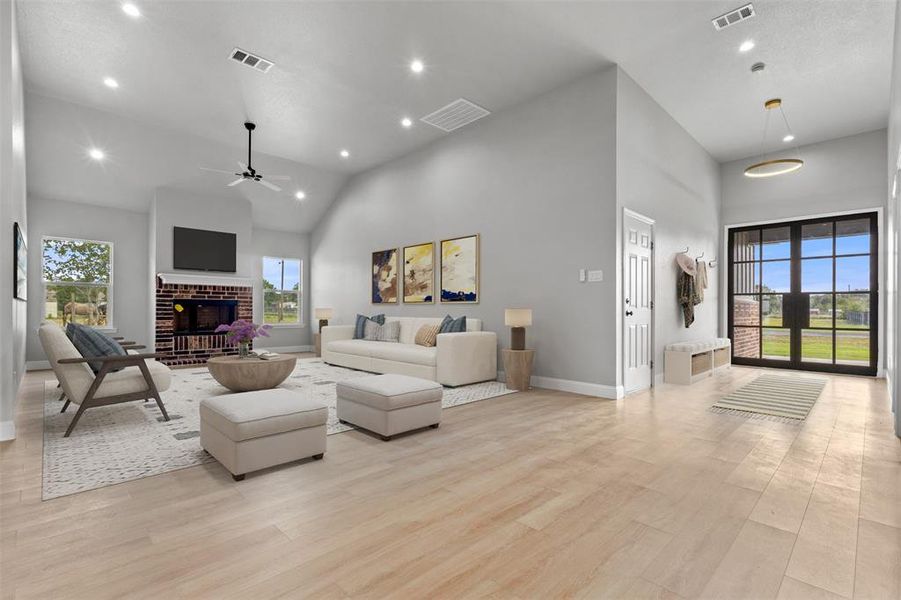 Living area with recessed lighting, high vaulted ceiling, light wood finished floors, a fireplace, and a ceiling fan