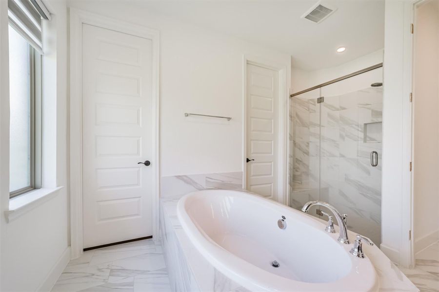 A luxurious soaker tub paired with a glass door leading to a tiled, enclosed walk-in shower. A luxurious soaker tub paired with a glass door leading to a tiled, enclosed walk-in shower.
