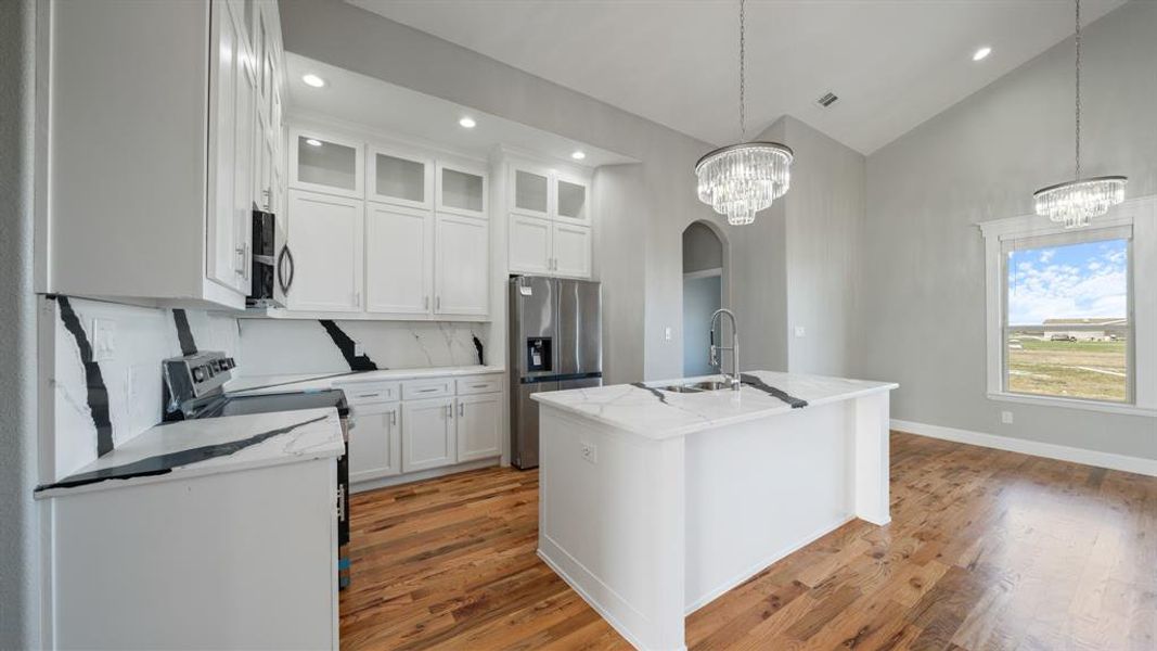 Kitchen featuring white cabinets, appliances with stainless steel finishes, a chandelier, and a sink