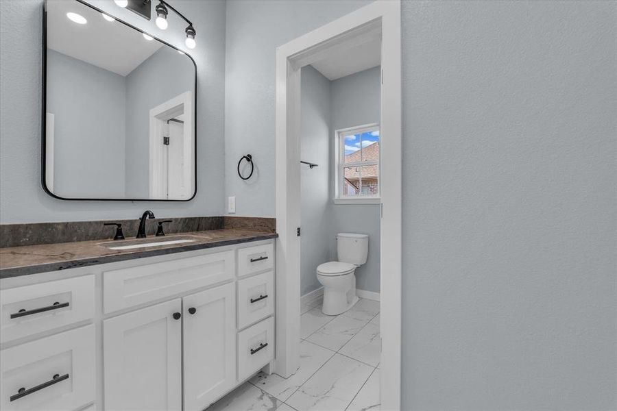 Bathroom featuring vanity and light marble finish floors Bathroom featuring vanity and light marble finish floors