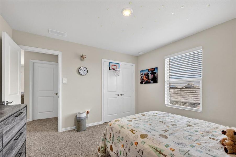 Bedroom with light colored carpet and a closet