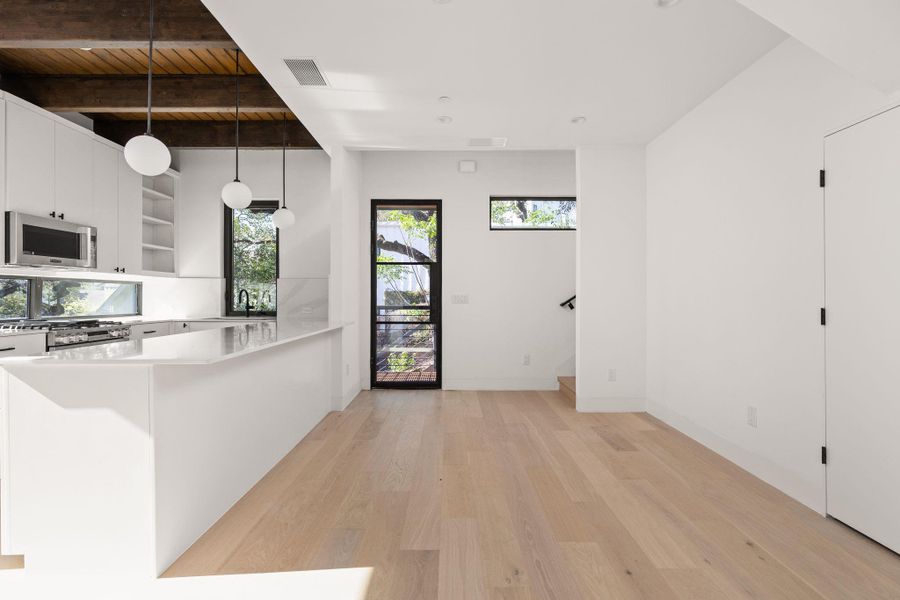 Kitchen featuring a peninsula, open shelves, stainless steel appliances, light wood finished floors, and white cabinetry