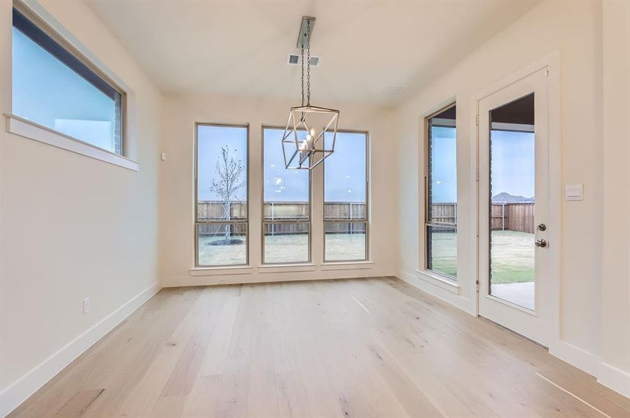 Unfurnished dining area with an inviting chandelier and light hardwood / wood-style flooring