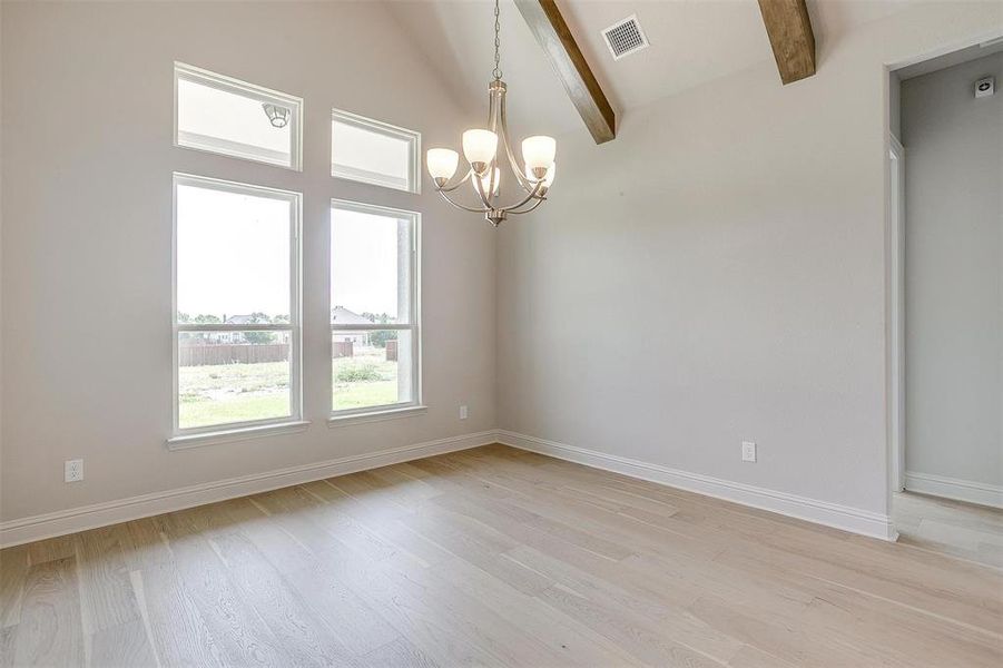 Unfurnished room featuring high vaulted ceiling, beam ceiling, an inviting chandelier, and light hardwood / wood-style floors