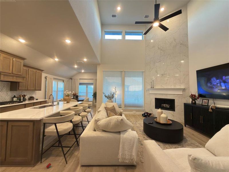 Living room with light wood finished floors, recessed lighting, a high ceiling, and a premium fireplace