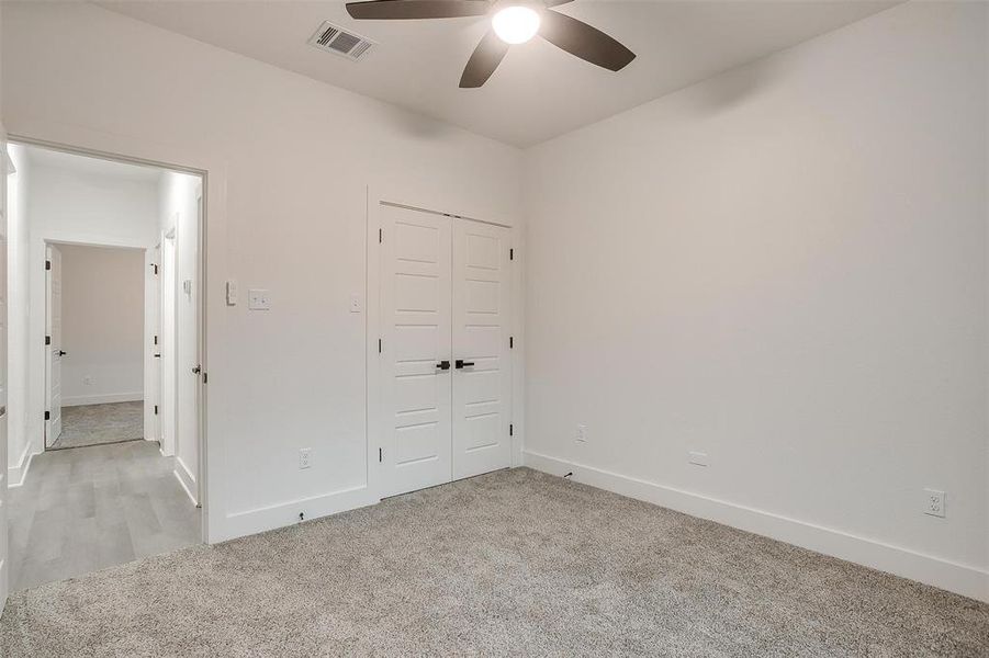 Unfurnished bedroom featuring light colored carpet, a closet, and ceiling fan