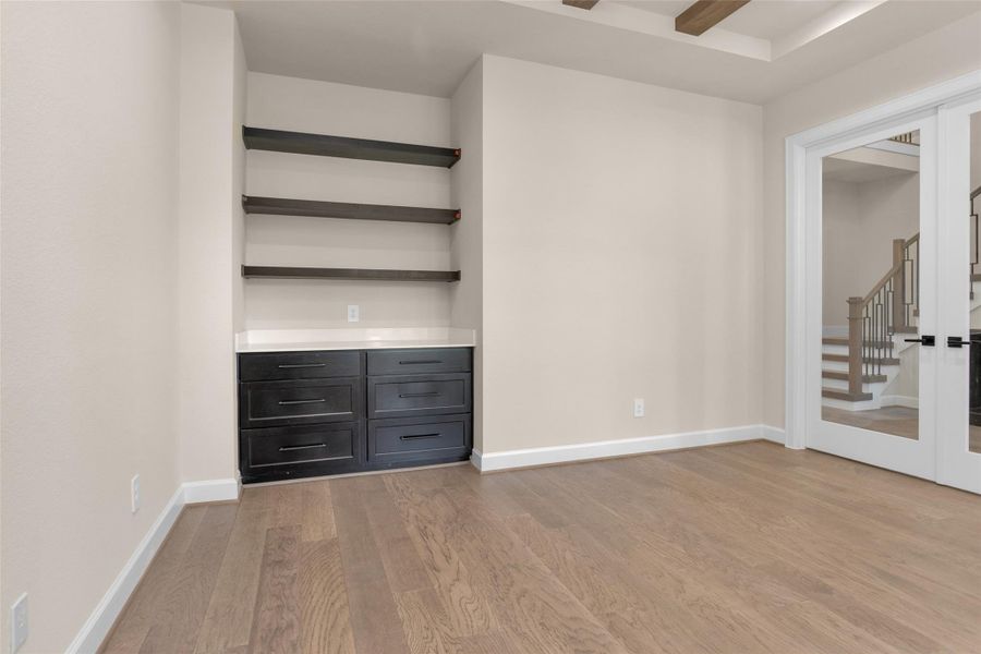 The home office features a tray ceiling with exposed beams and custom built-ins that offer both style and functional storage.