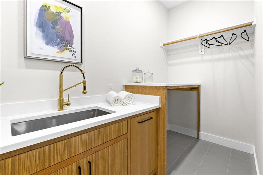 Laundry area with light tile patterned flooring and sink