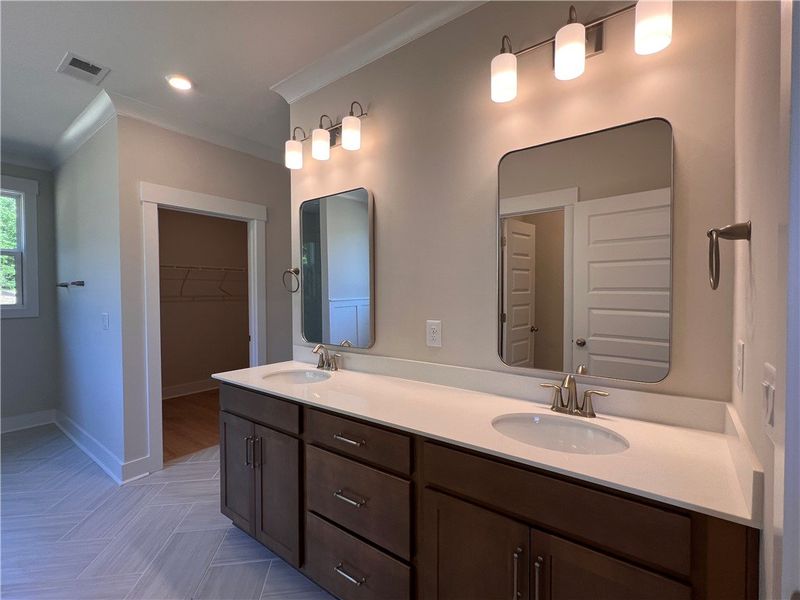 This spacious bathroom offers dual vanities, moder