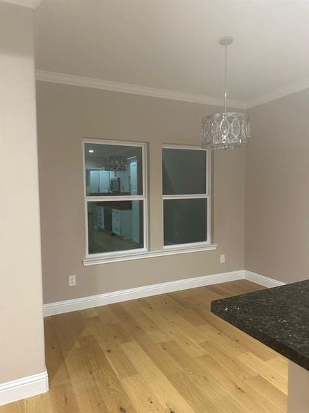 Unfurnished dining area featuring crown molding, an inviting chandelier, and hardwood / wood-style flooring