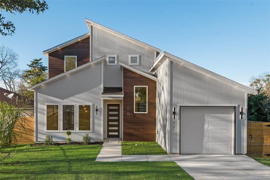 Contemporary house with a front lawn, concrete driveway, and a garage Contemporary house with a front lawn, concrete driveway, and a garage
