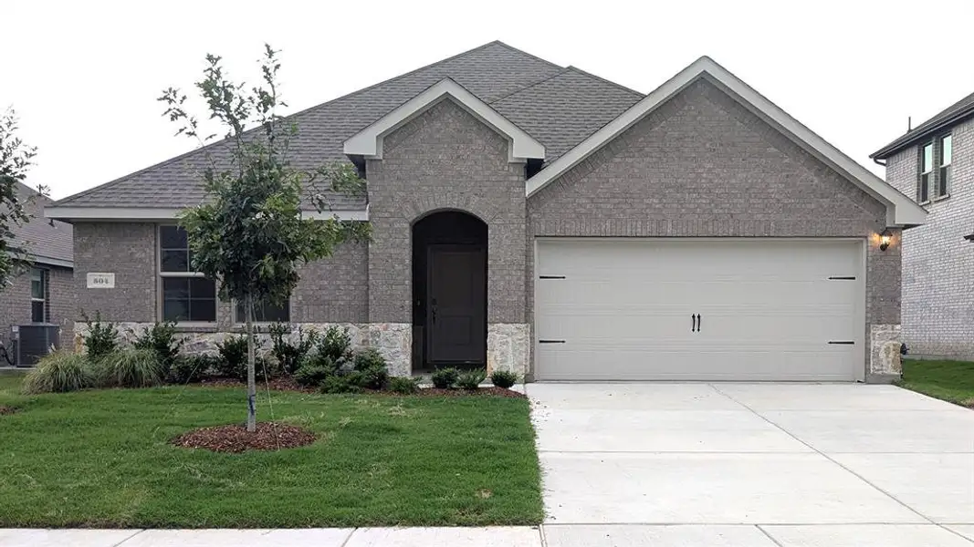 Brick facade featuring stone accents and a two-car garage Brick facade featuring stone accents and a two-car garage