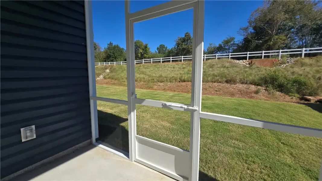 A screened porch overlooks a grassy, fenced yard u