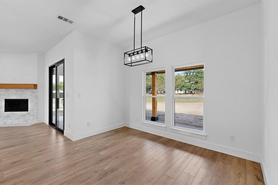 Unfurnished dining area with a fireplace, light wood-style flooring, and a chandelier