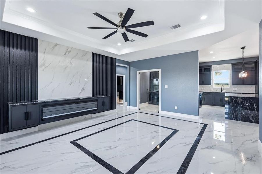 Unfurnished living room featuring light marble finish floors, a raised ceiling, recessed lighting, and ceiling fan