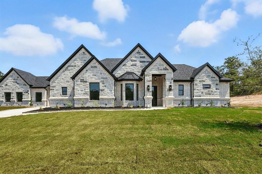 French country style house featuring a front lawn, stone siding, and brick siding