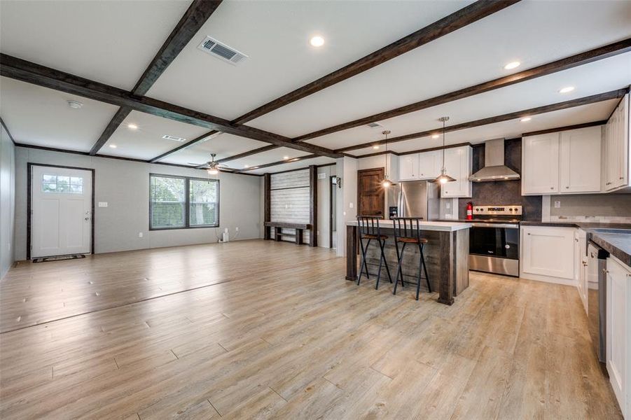 Dual tone kitchen with dark countertops, stainless steel appliances, a kitchen island, open floor plan, and backsplash Dual tone kitchen with dark countertops, stainless steel appliances, a kitchen island, open floor plan, and backsplash