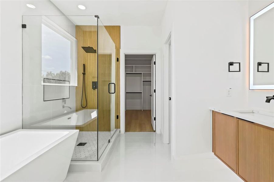 Full bathroom featuring a freestanding bath, a shower stall, vanity, a spacious closet, and light tile patterned floors
