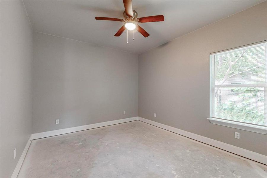 Unfurnished room featuring concrete flooring, plenty of natural light, and ceiling fan