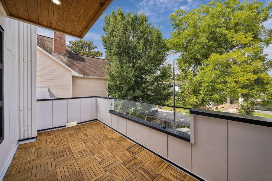 Enjoy relaxing on this spacious balcony with elegant wood-tile flooring and a modern glass railing, surrounded by lush greenery for an outdoor escape. Enjoy relaxing on this spacious balcony with elegant wood-tile flooring and a modern glass railing, surrounded by lush greenery for an outdoor escape.
