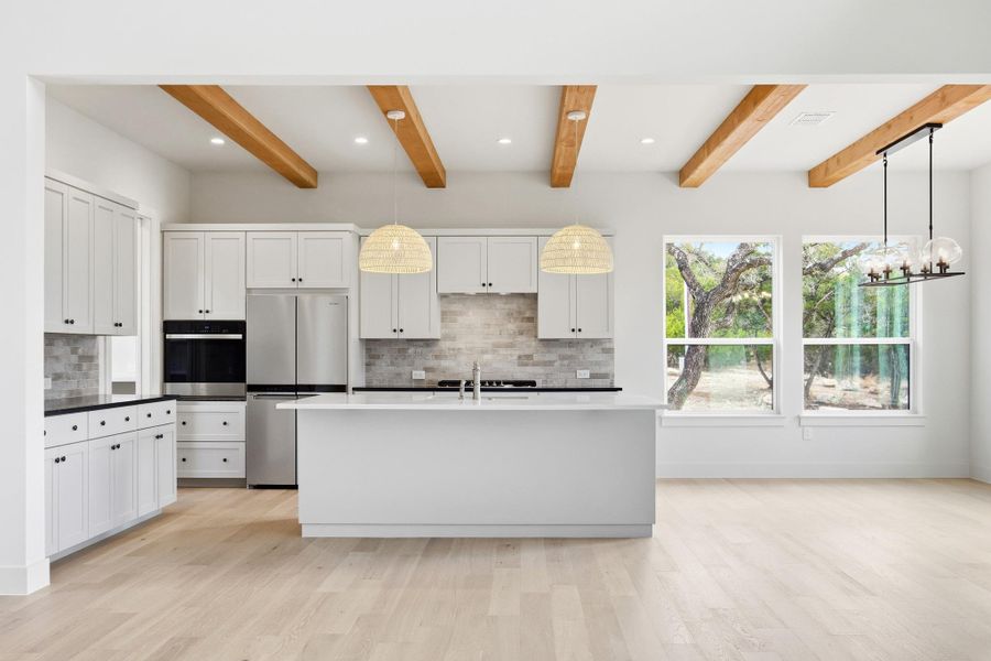Kitchen with island, exposed beams, and designer pendants