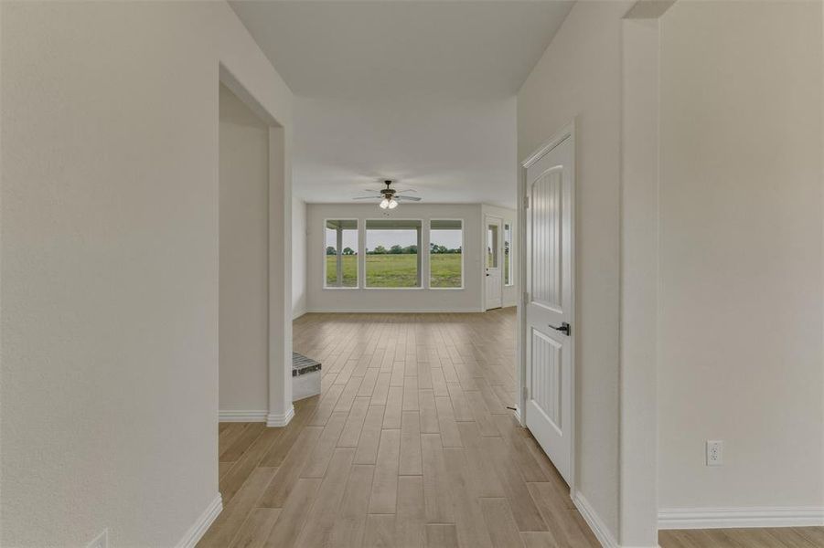 Expansive room featuring wood-finish flooring, a ceiling fan, and multiple large windows Expansive room featuring wood-finish flooring, a ceiling fan, and multiple large windows