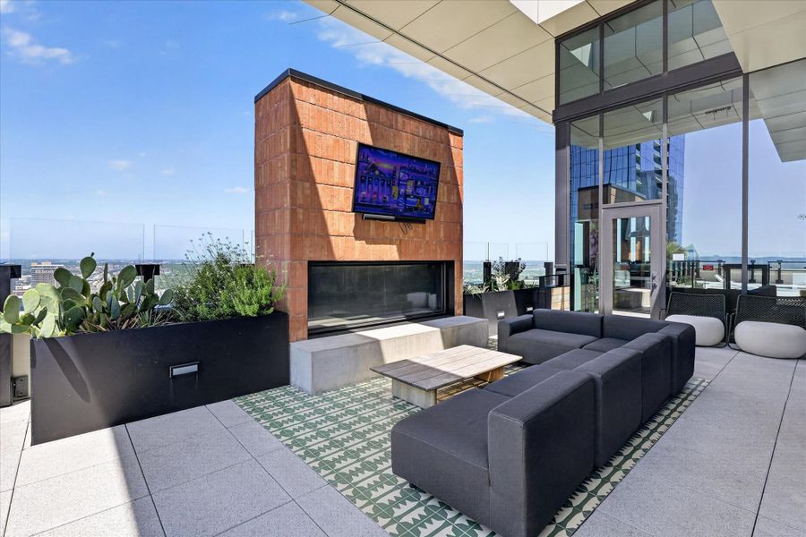 An airy rooftop terrace provides city views, complete with a modern outdoor fireplace and comfortable seating.