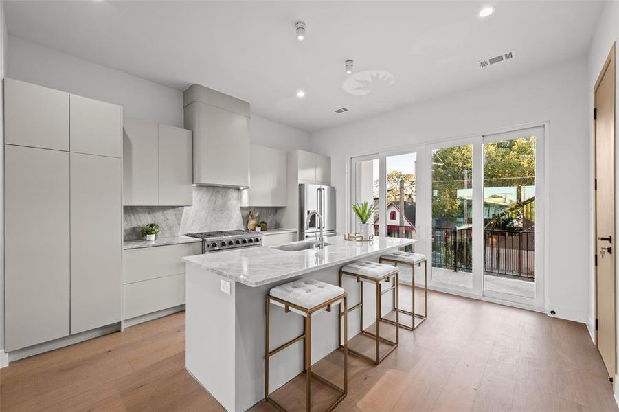 Kitchen with light stone counters, tasteful backsplash, modern cabinets, a kitchen island with sink, and recessed lighting