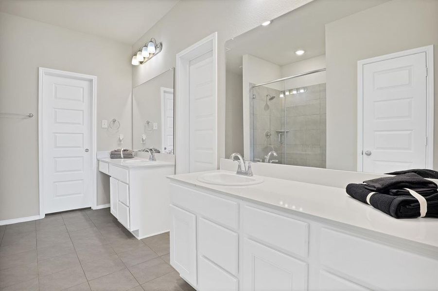 Bathroom featuring tile patterned flooring, vanity, and a shower with shower door