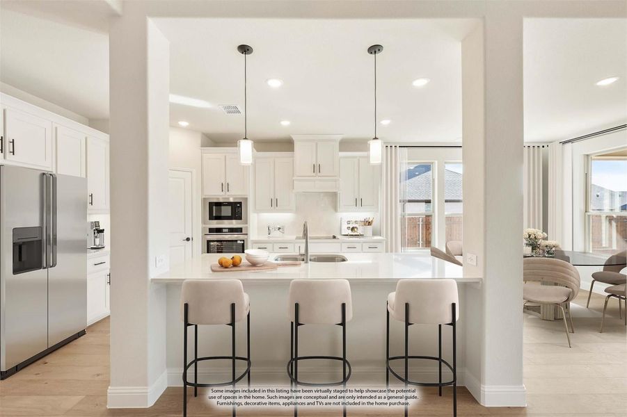 White kitchen with large island, three bar stools, pendant lights, and stainless steel appliances