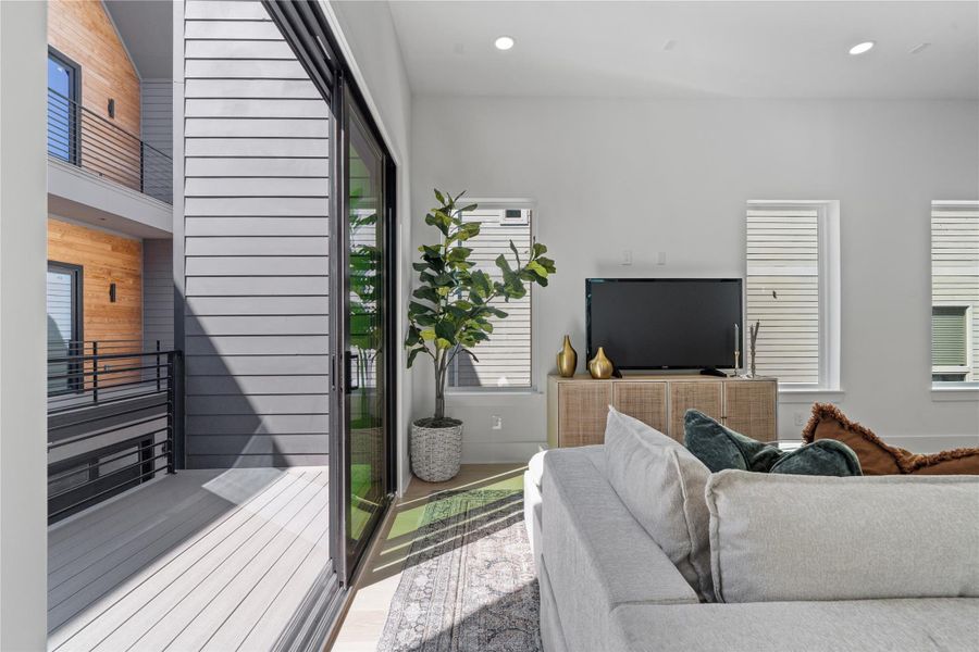 Oversized sliding glass doors extend the living space outdoors, opening to a private balcony tucked within the architectural envelope of the home. Natural light pours in through multiple exposures, reinforcing the home's bright and contemporary aesthetic. Oversized sliding glass doors extend the living space outdoors, opening to a private balcony tucked within the architectural envelope of the home. Natural light pours in through multiple exposures, reinforcing the home's bright and contemporary aesthetic.