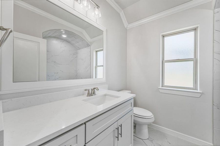Bathroom with light marble finish floors, vanity, ornamental molding, and a shower