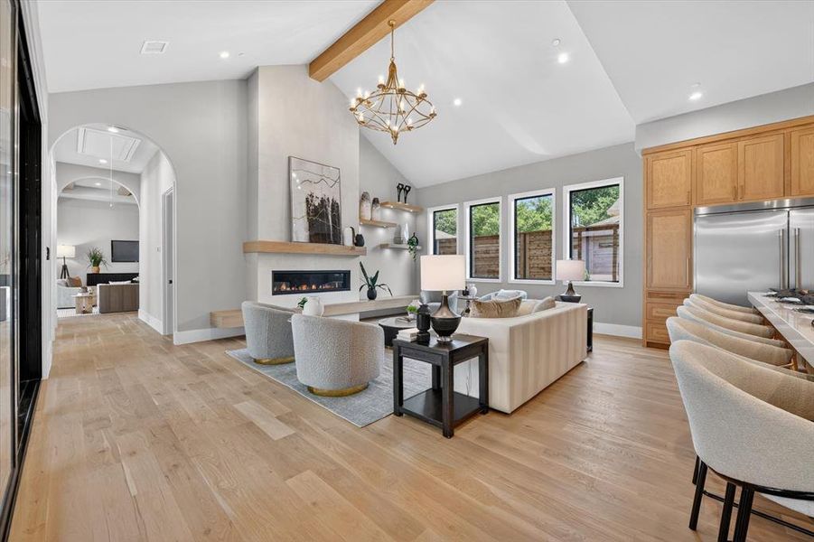 Vaulted ceiling with an exposed wood beam, wide plank wood-finish flooring, and a linear fireplace with a wood mantle Vaulted ceiling with an exposed wood beam, wide plank wood-finish flooring, and a linear fireplace with a wood mantle