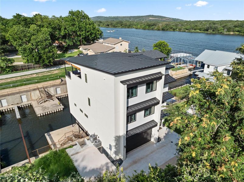 This modern, multi-story home offers stunning waterfront views and direct water access. Surrounded by lush greenery, it features a sleek design with a flat roof and multiple balconies. Ideal for those seeking a serene waterfront lifestyle.