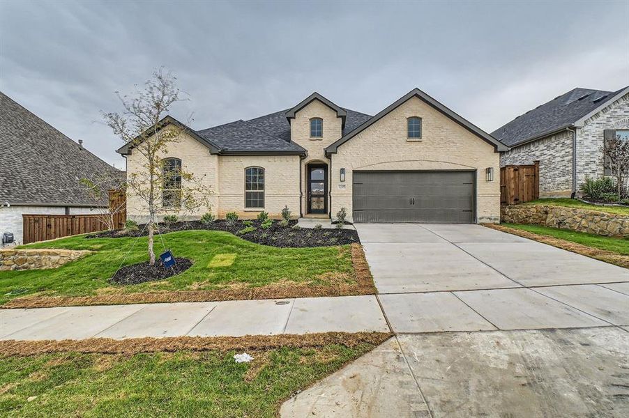 French country inspired facade featuring a front yard and a garage