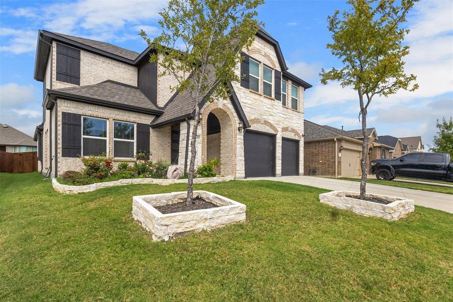 View of front of home with stone siding, roof with shingles, concrete driveway, an attached garage, and brick siding