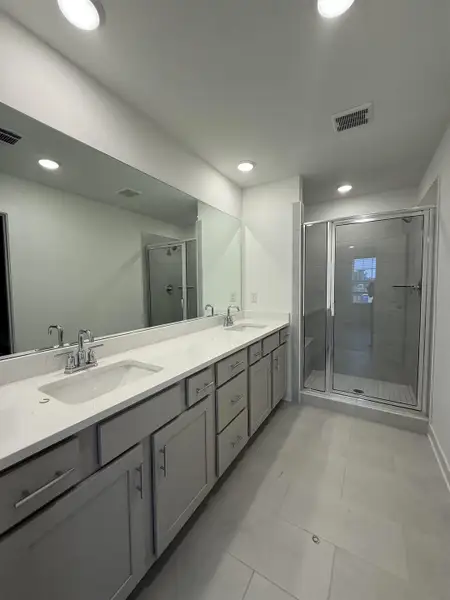 Full bath featuring double vanity, a shower stall, and recessed lighting