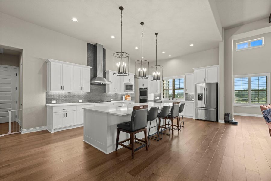 A grand, modern kitchen offers extensive counter space, sleek cabinetry, and integrated appliances, illuminated by stylish pendant lighting. A grand, modern kitchen offers extensive counter space, sleek cabinetry, and integrated appliances, illuminated by stylish pendant lighting.