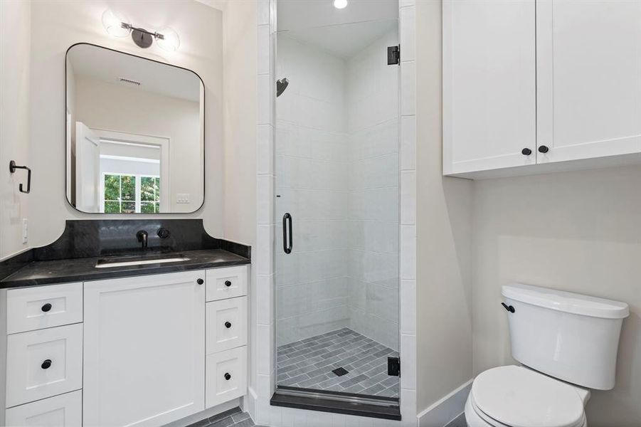 Bathroom with a shower with shower door, toilet, and vanity