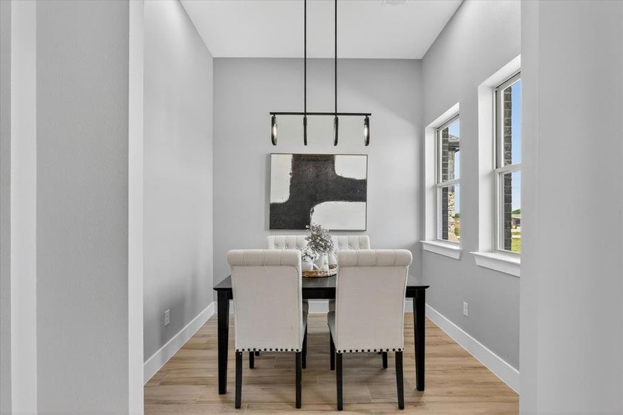 Dining area featuring wood-finish flooring, two large windows, a black linear chandelier, and light gray walls