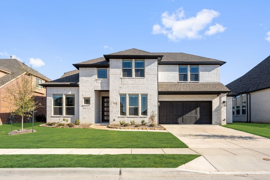 Two-story home with white brick exterior, dark two-car garage, and green front lawn Two-story home with white brick exterior, dark two-car garage, and green front lawn